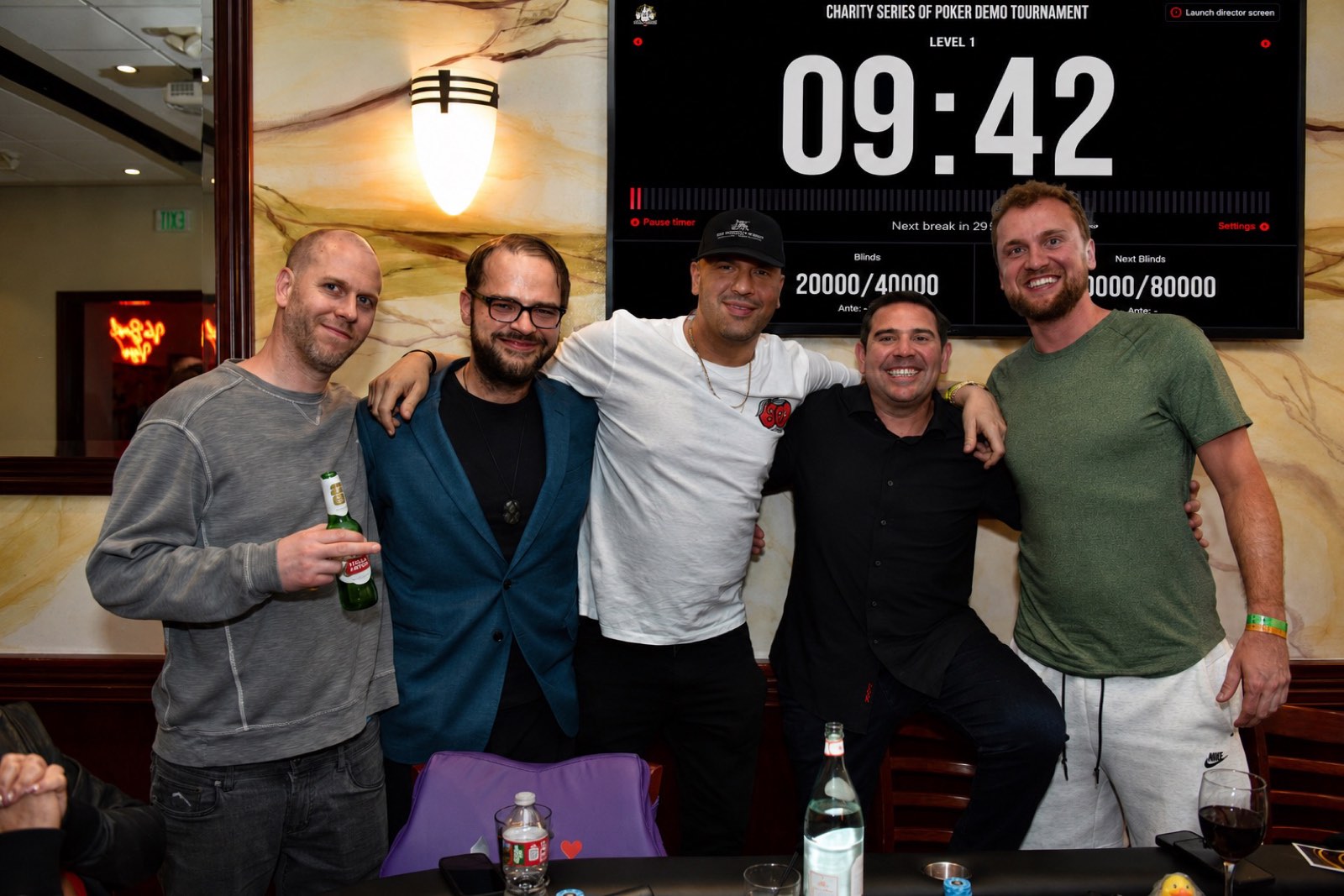 Five players together in front of the Charity Series of Poker tournament clock