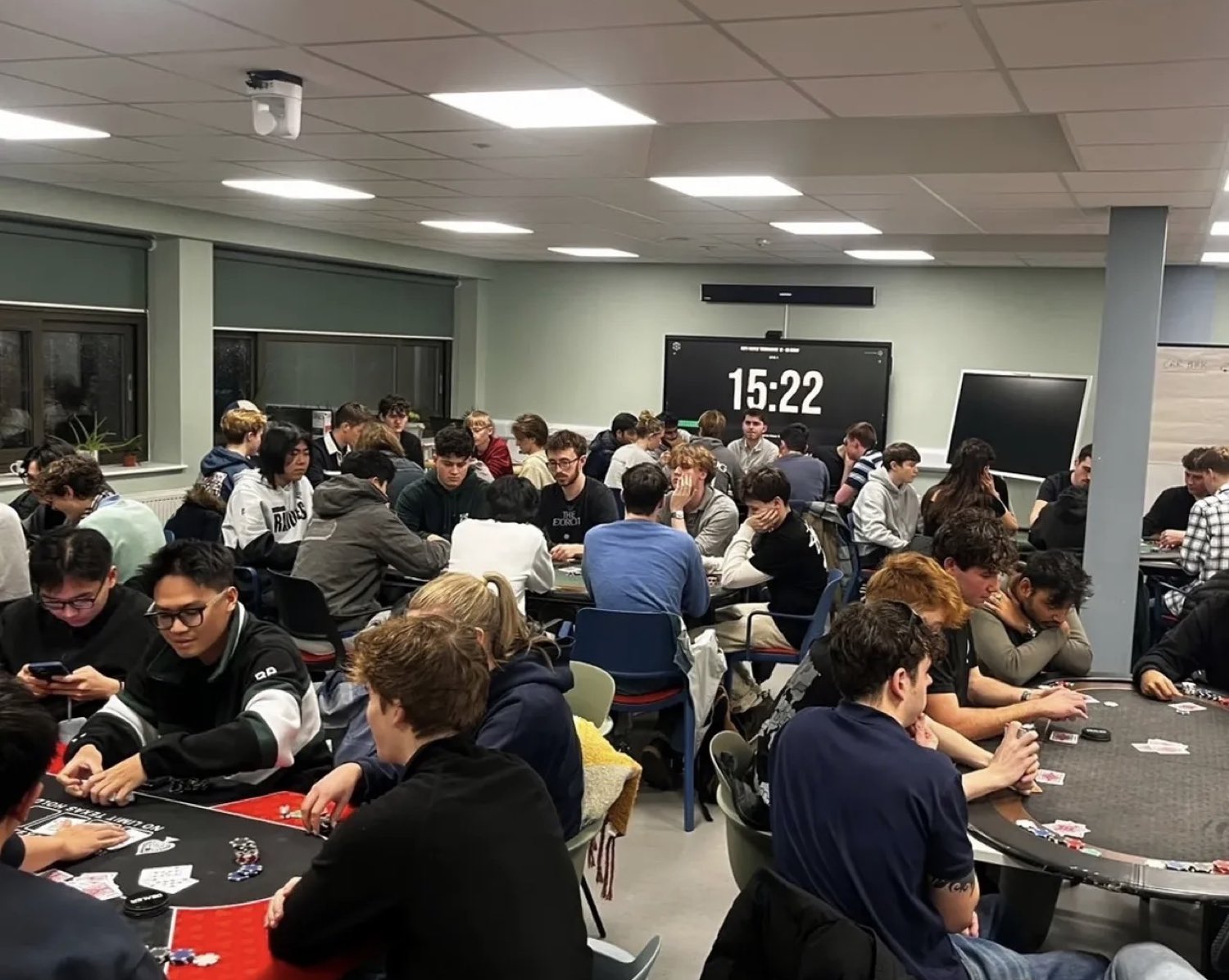 A packed University of Exeter Poker Society student tournament, The Poker Timer clock on the screen