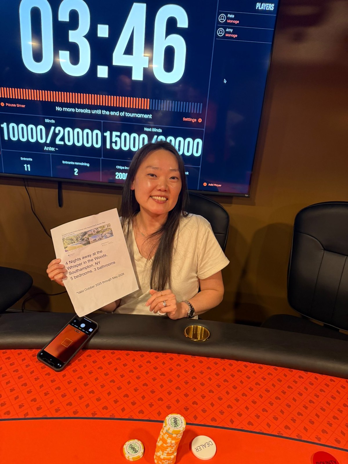 A Port Washington Poker Club player holding up a prize in front of The Poker Timer