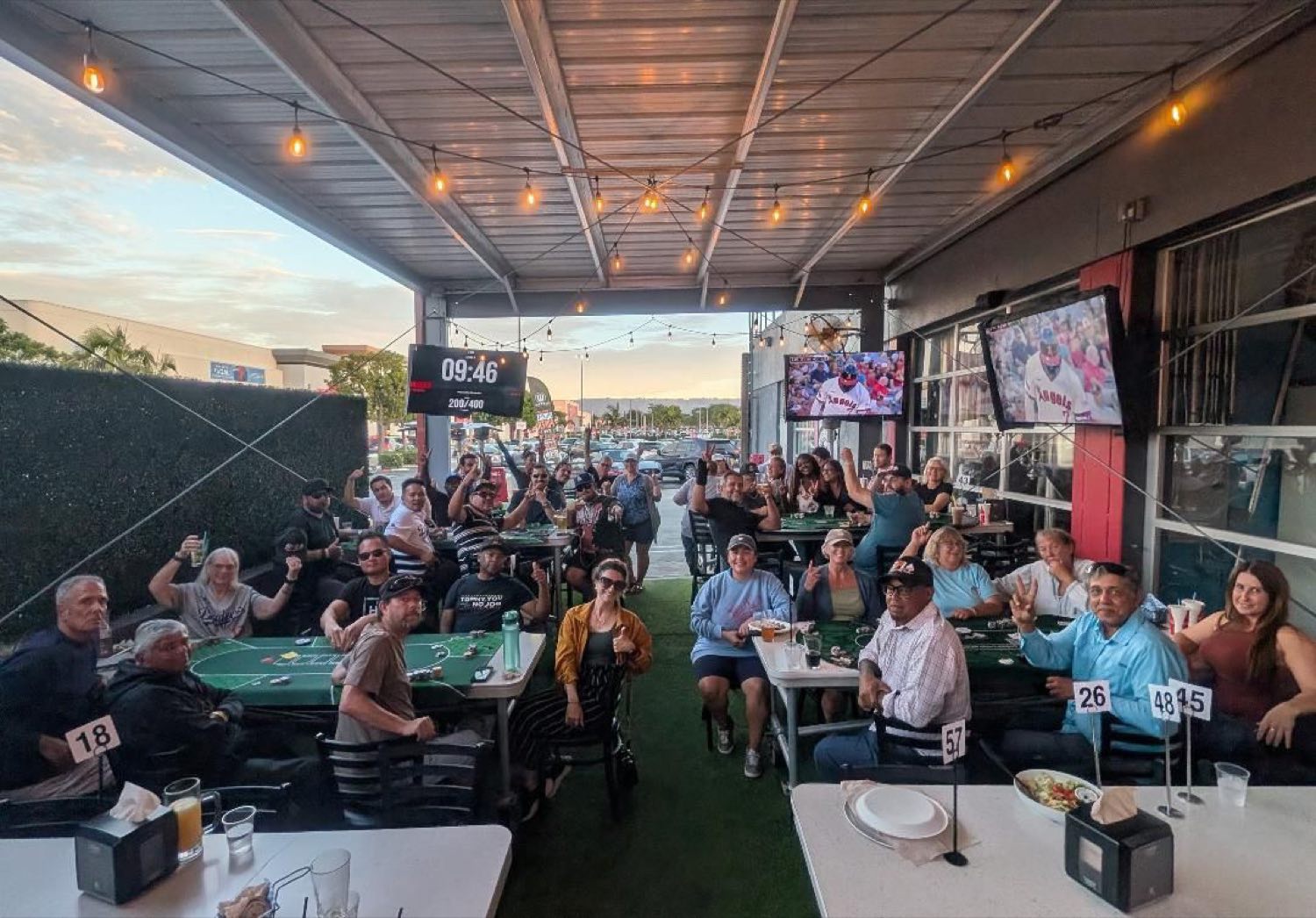 A large Sunshine Poker League group at an outdoor poker night, The Poker Timer clock on screen